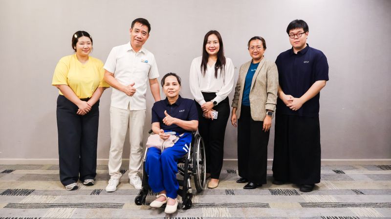 Picture 2: Participants pose for a group photo. Ms. Nongnuch Maytarjittipun is seated in a wheelchair in the center and Mr. Asdang Sukwises stands to her left