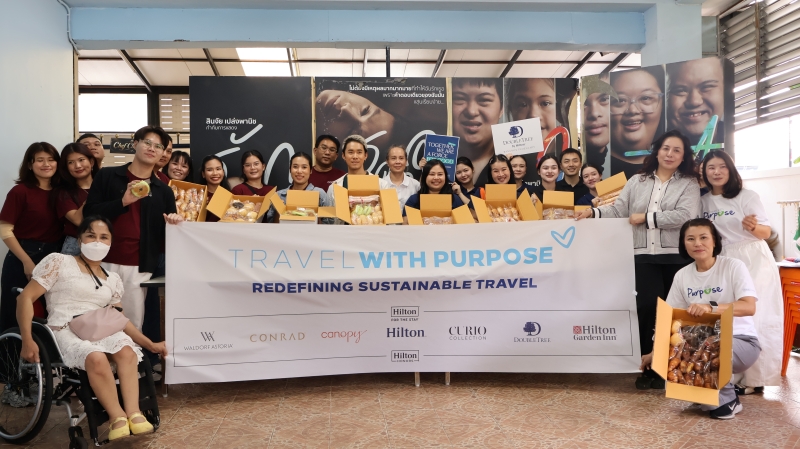 Representatives from three hotels hold a 'Travel with Purpose' sign and freshly baked bread while posing for a photo.