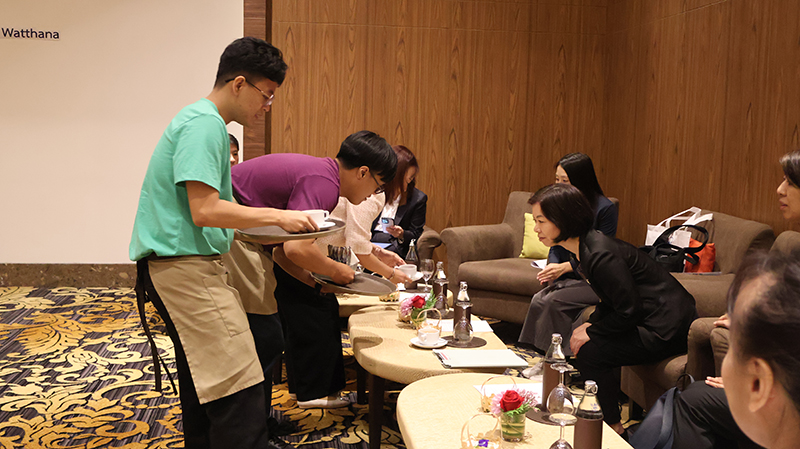 Picture 3: Trainee in purple T-shirt and Trainee in green T-shirt (left) serving drinks and snacks to Ms. Komahashi Rie - Senior Representative (right).