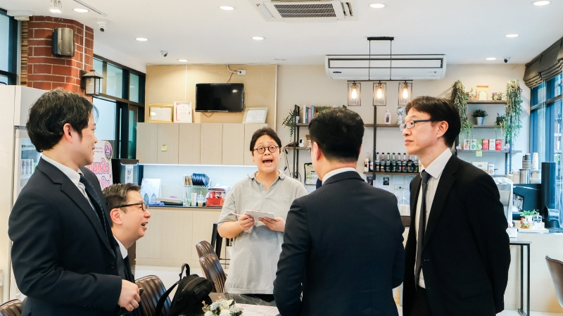 A staff with a disability takes order from the JICA representatives.