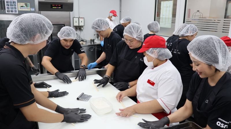Participants knead a dough with trainers with disabilities.