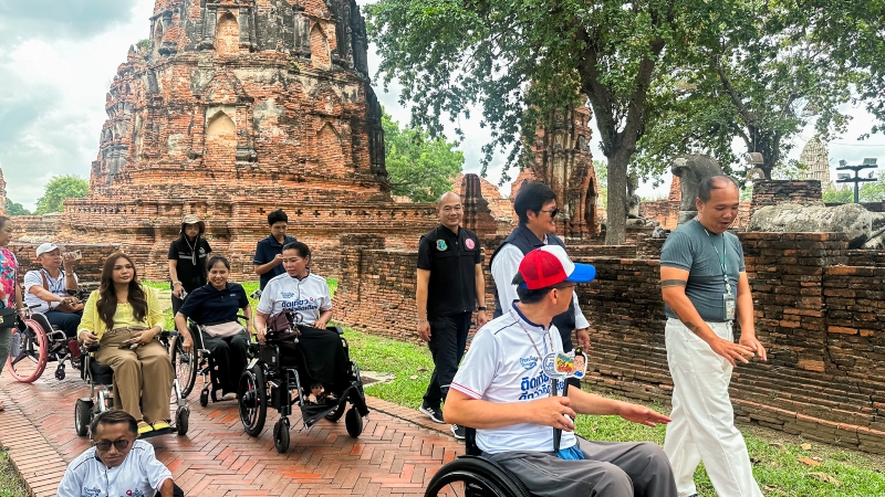 ภาพที่ 5: ผู้เข้าร่วมที่ใช้รถเข็นเที่ยวชมสถานที่ขณะที่ผู้นำชมให้ข้อมูลโดยมีพระปรางค์อยู่ด้านหลัง
