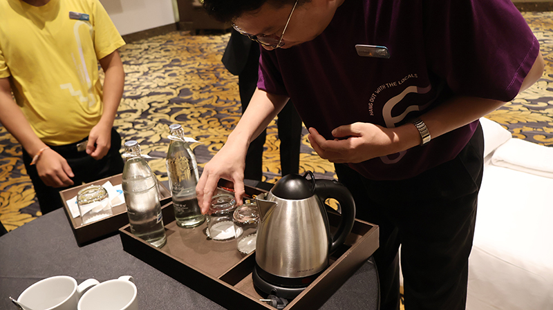 Picture 6: Trainee in purple T-shirt arranging drinking glasses.