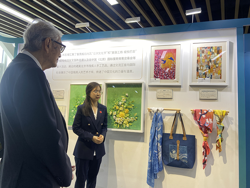 Picture 6: A staff member (center) introduces products made by persons with disabilities to Dr. Tej Bunnag (left)