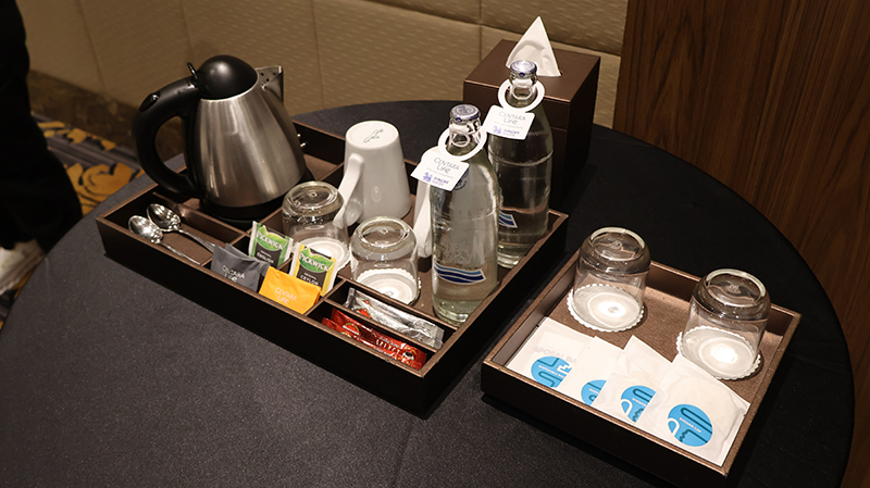 Picture 7: Tea pot, tea spoons, coffee mug, drinking glasses, water bottles, tea bags, coffee bags arranged in neatly order.