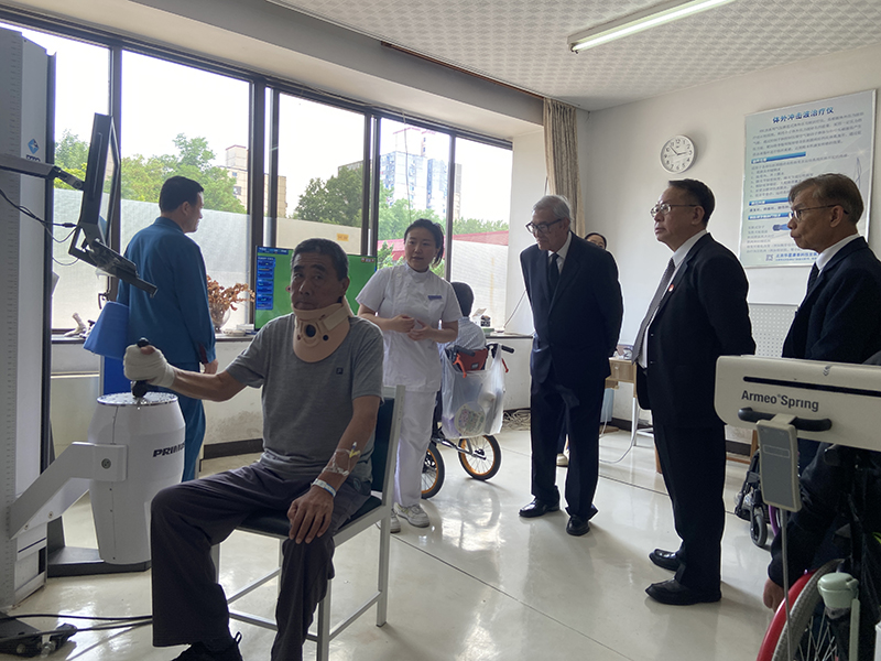 Picture 9: From right to left, Mr. Somchai Rungsilp, Mr. Piroon Laismit, and Dr. Tej Bunnag observe a staff member (center) demonstrating physical therapy for persons with disabilities
