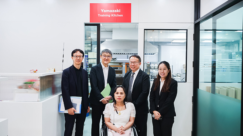 Picture 12: From left to right, Mr. SAKUDO Shunsuke, Mr. KOBAYASHI Hiroyuki, Mr. Piroon Laismit, Ms. Nuntaporn Sittidetboripat, and Ms. Nongnuch Maytarjittipun (seated in a wheelchair in the center) pose for a group photo