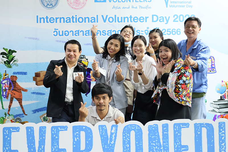 APCD staff posed for a group photo in front of the "International Volunteer Day 2023" panel.	