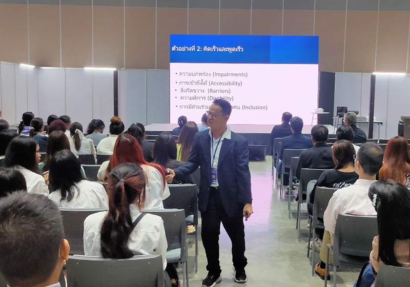 Mr. Watcharapol Chuengcharoen conducted Disability Equality Training or DET in short. He handed the microphone to a participant, encouraging her to share her thoughts on disability inclusion.