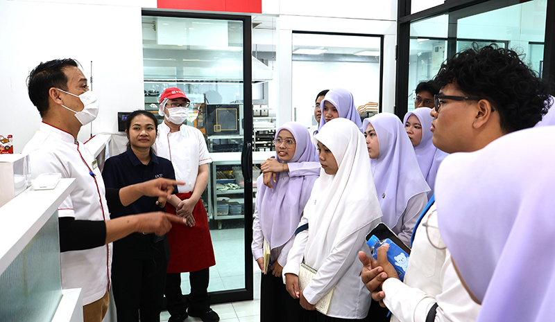 ภาพที่ 4: นางสาวศิริพร ประเสริฐชาติ นำคณะนักศึกษาเยี่ยมชม 60+ Plus Bakery & Chocolate Café และ 60+ Plus Kitchen by CP ซึ่งเป็นโครงการต้นแบบการจ้างงานและและธุรกิจที่คนพิการมีส่วนร่วม โดยพนักงานผู้พิการมีบทบาทสำคัญในการดำเนินกิจการทั้งด้านการผลิตขนมและการให้บริการ พร้อมกันนี้นักศึกษาได้เรียนรู้และแลกเปลี่ยนประสบการณ์การทำงานจากเชฟประจำร้านเบเกอรี่ ที่ทำงานร่วมกับพนักงานผู้พิการ รวมถึงสอนพนักงานผู้พิการทำเบเกอรี่อย่างใกล้ชิด 
