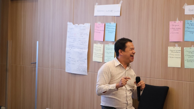 รูปที่ 6 : นายวัชรพล จึงเจริญ แจ้งผู้เข้าร่วมประชุมด้านโลจิสติกส์ และขอความร่วมมือให้ผู้เข้าร่วมการประชุมประเมินผลการประชุม