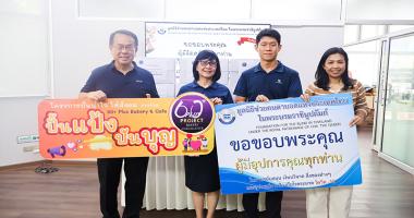 Picture 1: A group photo featuring Mr. Piroon Laismit, Executive Director of APCD (far left), and representatives from the Bangkok School for the Blind (center) holding a "Pun Pang, Pun Boon" campaign sign, alongside Ms. Wilailekha Somprach, Manager of APCD 60+ Plus Projects (far right), holding a thank-you sign, with boxes of bread stacked in the background.