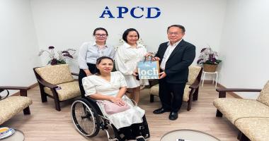 Picture 1: From left to right, Ms. Nitwari Sikon, Ms. Kingkarn Siriwat (left) and Mr. Piroon Laismit (right), both holding a gift together and Ms. Nongnuch Maytarjittipun (seated in a wheelchair in front of Ms. Nitwari Sikon)